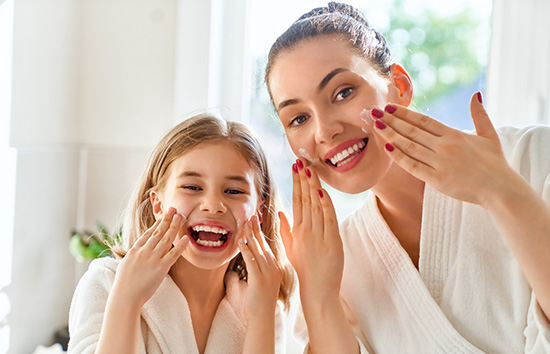 A photo of a woman and daughter applying skincare products.
